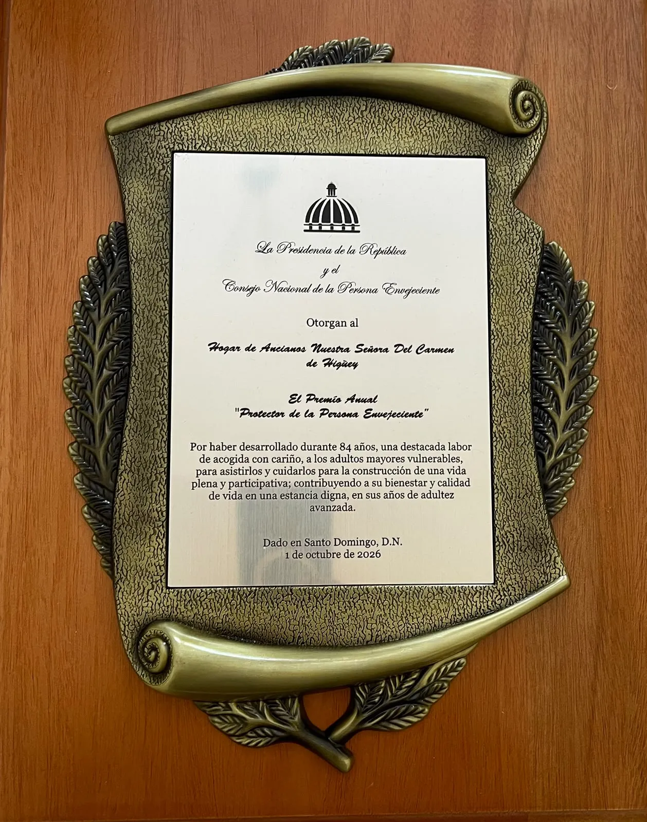 Placa del Premio Anual Protector de la Persona Envejeciente otorgado al Hogar de Ancianos Nuestra Señora del Carmen de Higüey por sus 84 años de labor, el 1 de octubre de 2026